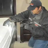 Bed bug inspection technician checking a mattress and bed frame for signs of infestation in Orange, CA