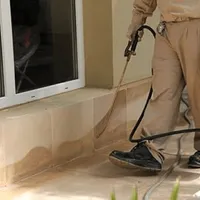 General pest control technician spraying exterior perimeter around a home in Orange, CA