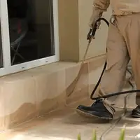 General pest control technician spraying exterior perimeter around a home in Orange, CA
