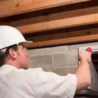 Termite inspection technician checking a basement wall and framing for termite activity in Orange, CA